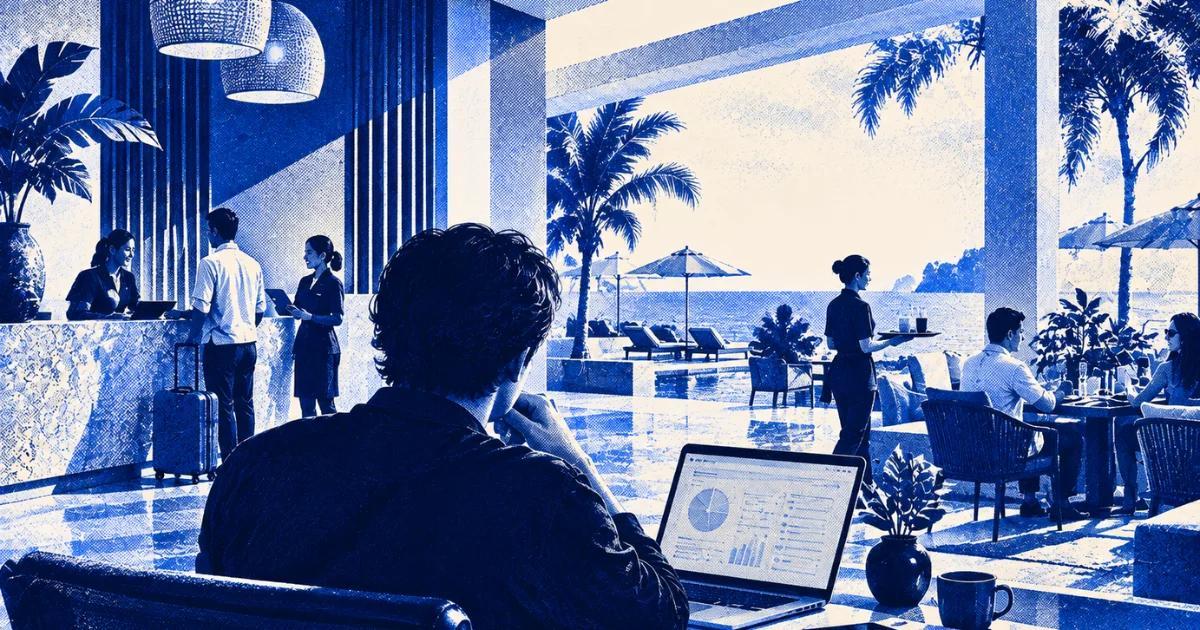 Person using a laptop in a modern resort, with hotel staff and guests in the background.